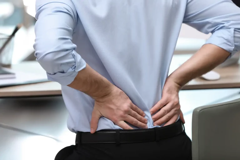 Mann mit Rückenschmerzen am schreibtisch-Körperhaltung und chronische Schmerzen