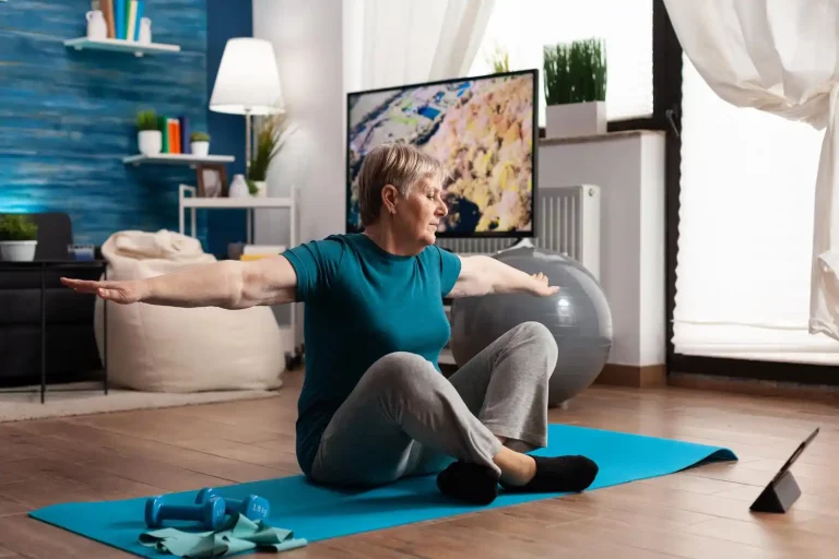 Rentnerin auf einer Yoga-Matte dehnt ihre Arme